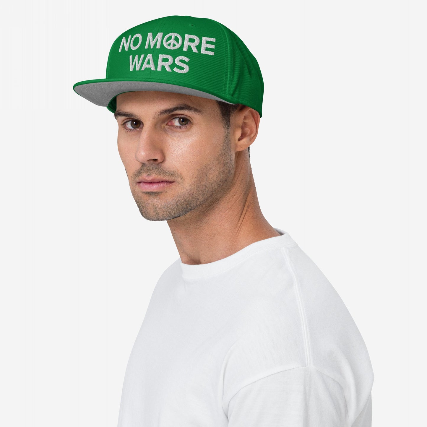 Young man wears the No More Wars Hat, a green cap highlighting anti-war sentiment with NO MORE WARS embroidered, featuring a peace symbol. Ideal for protests or daily wear, supporting global peace.