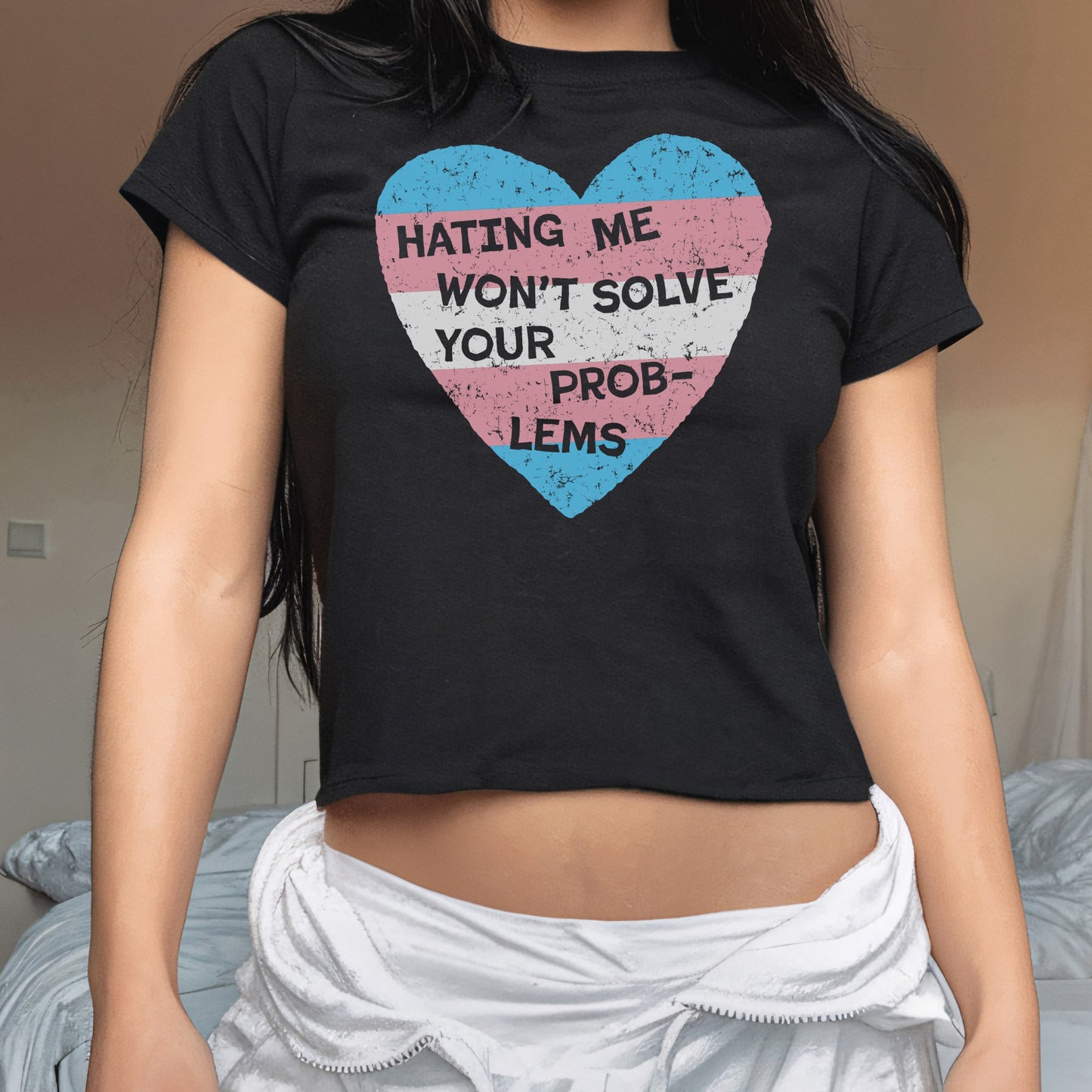 Person wearing the No Trans Hate Women's Baby Tee with a distressed trans pride heart and empowering slogan, showcasing solidarity and resistance against bigotry, paired with a light-colored garment around the hips.