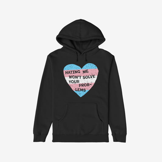 No Trans Hate Hoodie features a black pullover design with a large heart graphic in trans pride colors and the slogan “HATING ME WON’T SOLVE YOUR PROBLEMS,” embodying resilience and solidarity.