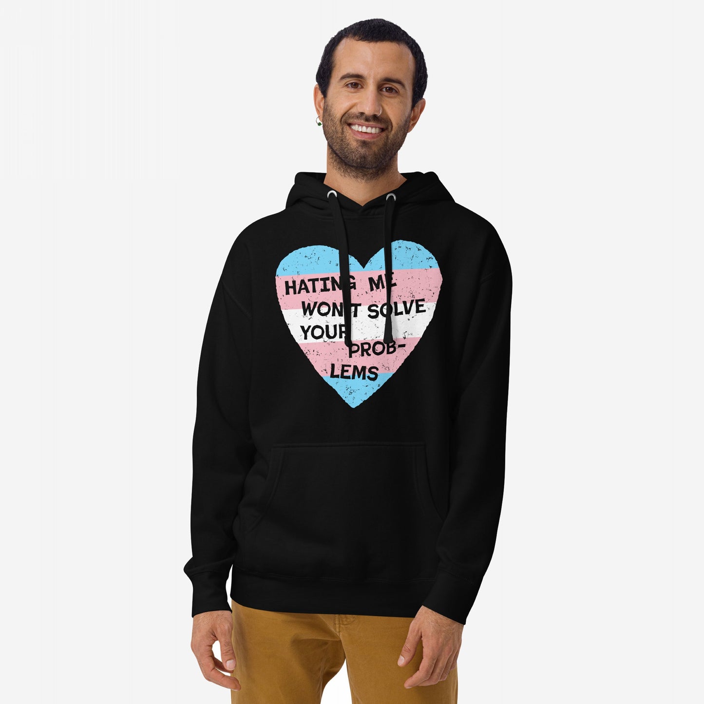 No Trans Hate Hoodie featuring a heart with transgender-pride colors and the slogan Hating me won’t solve your problems, worn by a person against a light background.