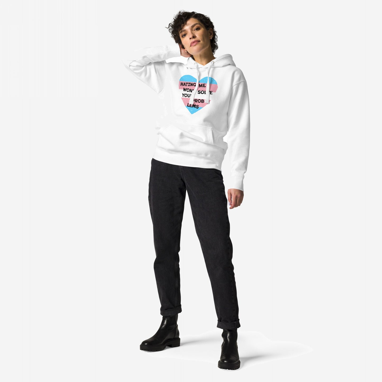 Model wearing the No Trans Hate Hoodie, featuring a heart graphic and message on a white pullover, paired with black jeans and chunky boots, exemplifying resilience and solidarity in style.