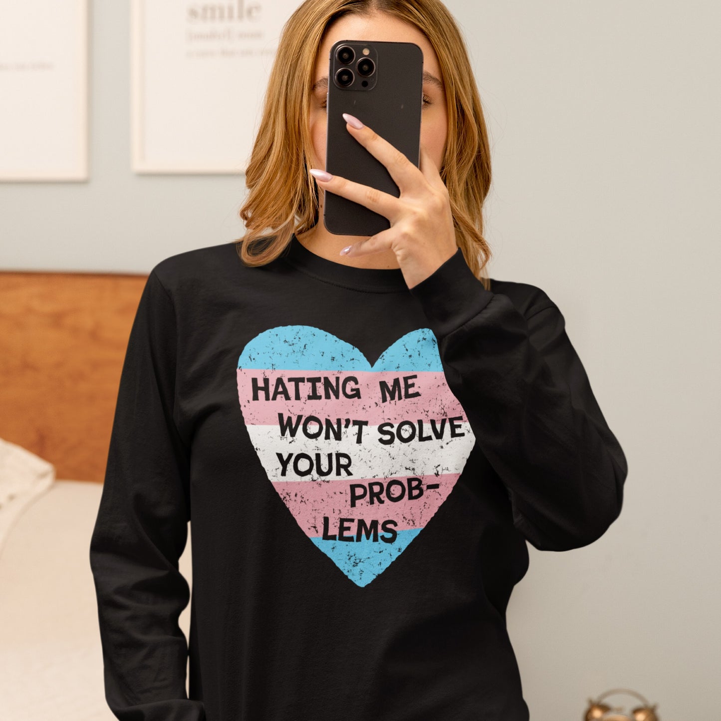 Mirror selfie of a person wearing the No Trans Hate T-shirt featuring a heart in trans pride colors and “HATING ME WON’T SOLVE YOUR PROBLEMS” slogan, embodying identity and resistance.