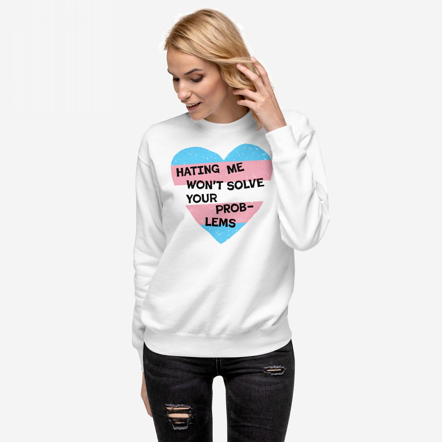 No Trans Hate Hoodie & Sweatshirt featuring a bold heart design with the slogan Hating Me Won’t Solve Your Problems, symbolizing resilience and trans rights. Worn by a woman with blonde hair and black ripped jeans.