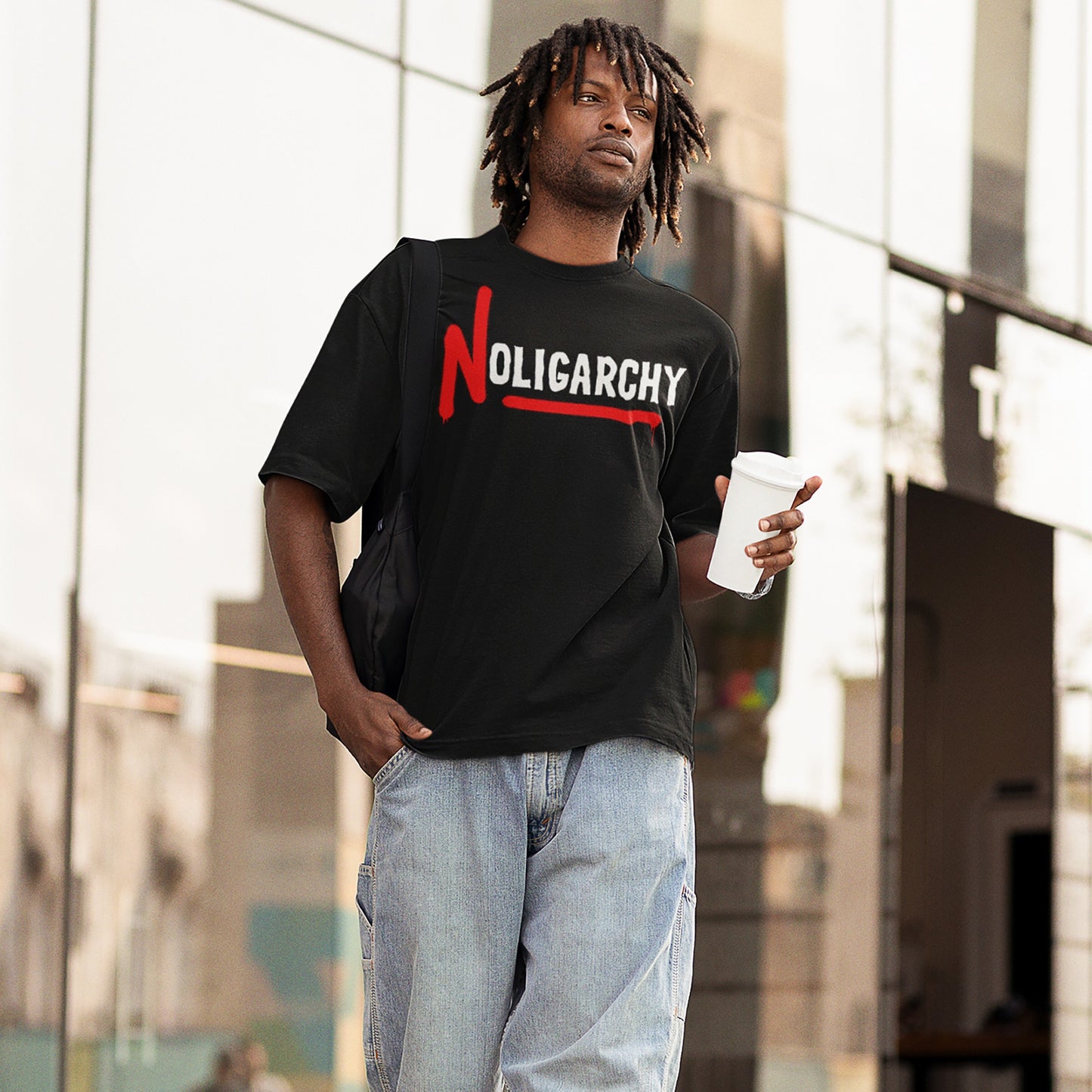 Young man wearing the No Oligarchy T-shirt, featuring bold white lettering with a red spray-painted N and underline, embodying street-style defiance and a stance against oligarchies.