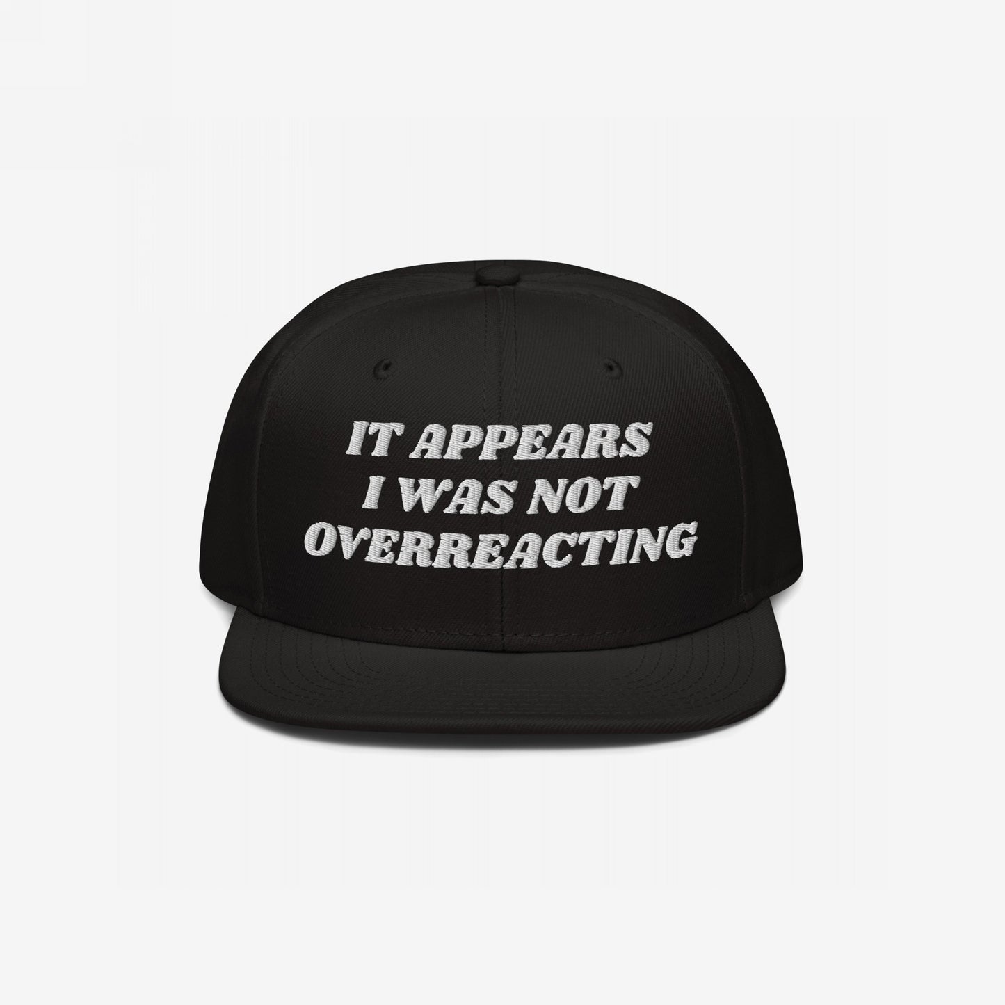 Black flat-bill snapback cap with white embroidered text: “It appears I was not overreacting.” The Overreacting Hat signifies resilience against political gaslighting, supporting progressive voices demanding justice and equality.