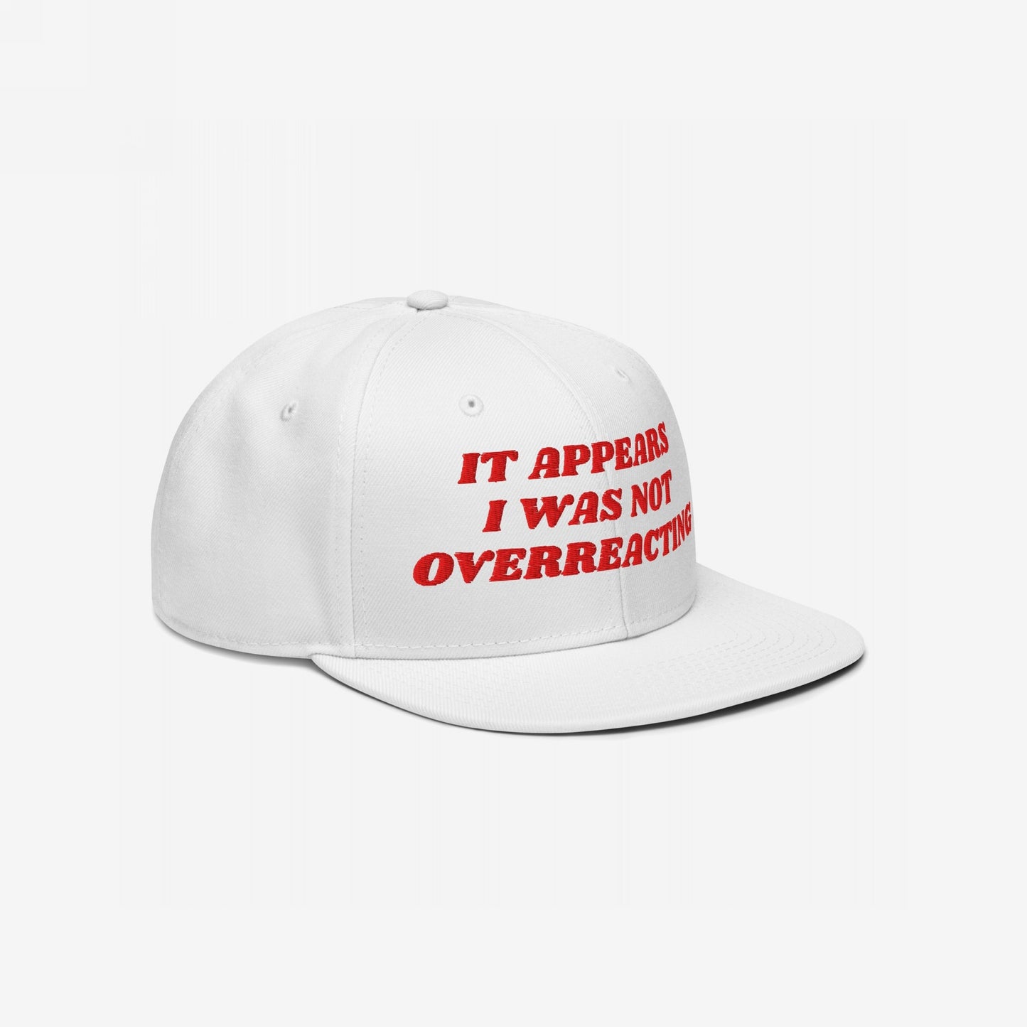 The Overreacting Hat features bold red embroidery stating IT APPEARS I WAS NOT OVERREACTING on a white snapback cap, embodying a fearless stance against political gaslighting and injustice.