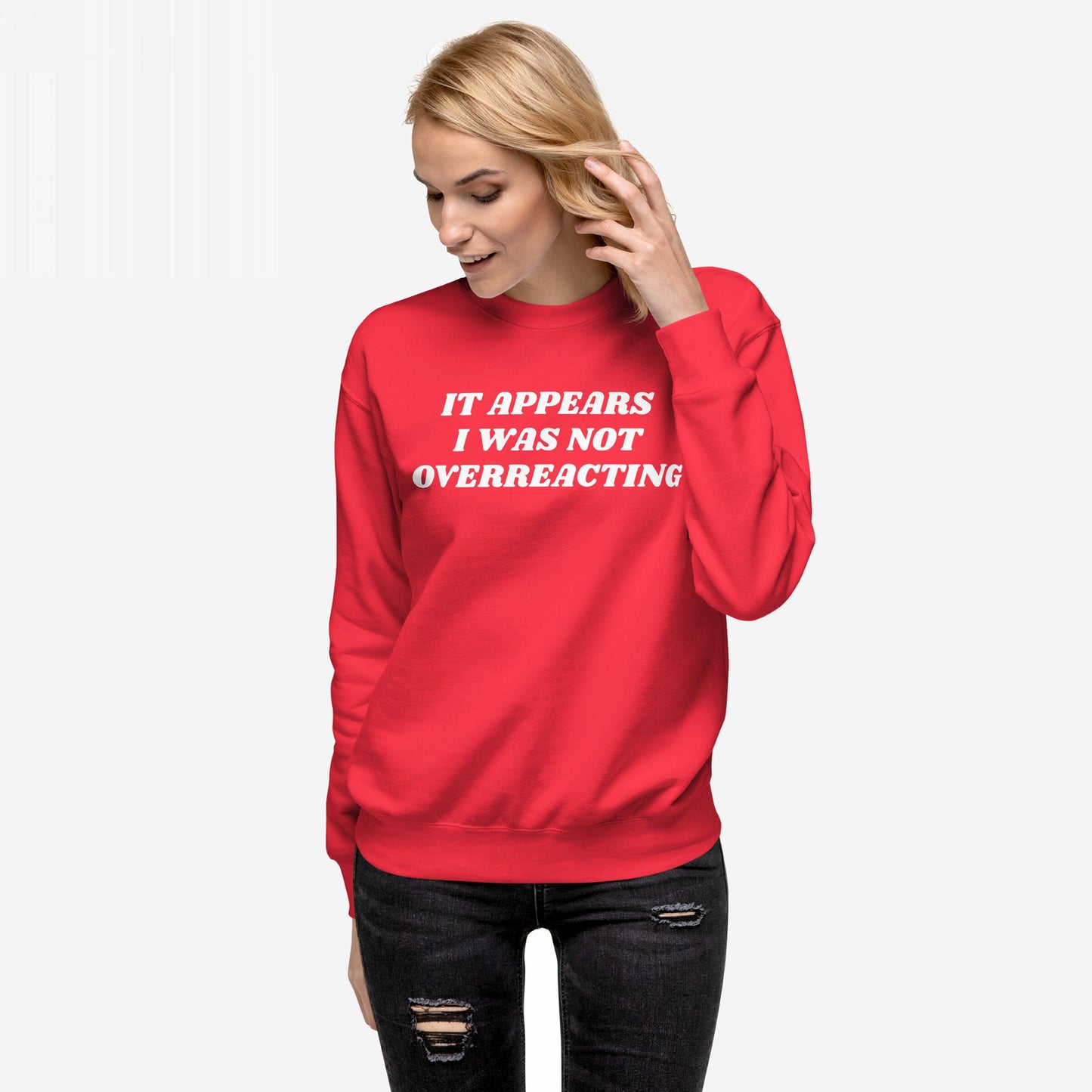 Overreacting Hoodie & Sweatshirt: A light-skinned woman wears a bold red crewneck with “IT APPEARS I WAS NOT OVERREACTING” in white block letters, embodying resistance and unapologetic truth against oppressive systems.