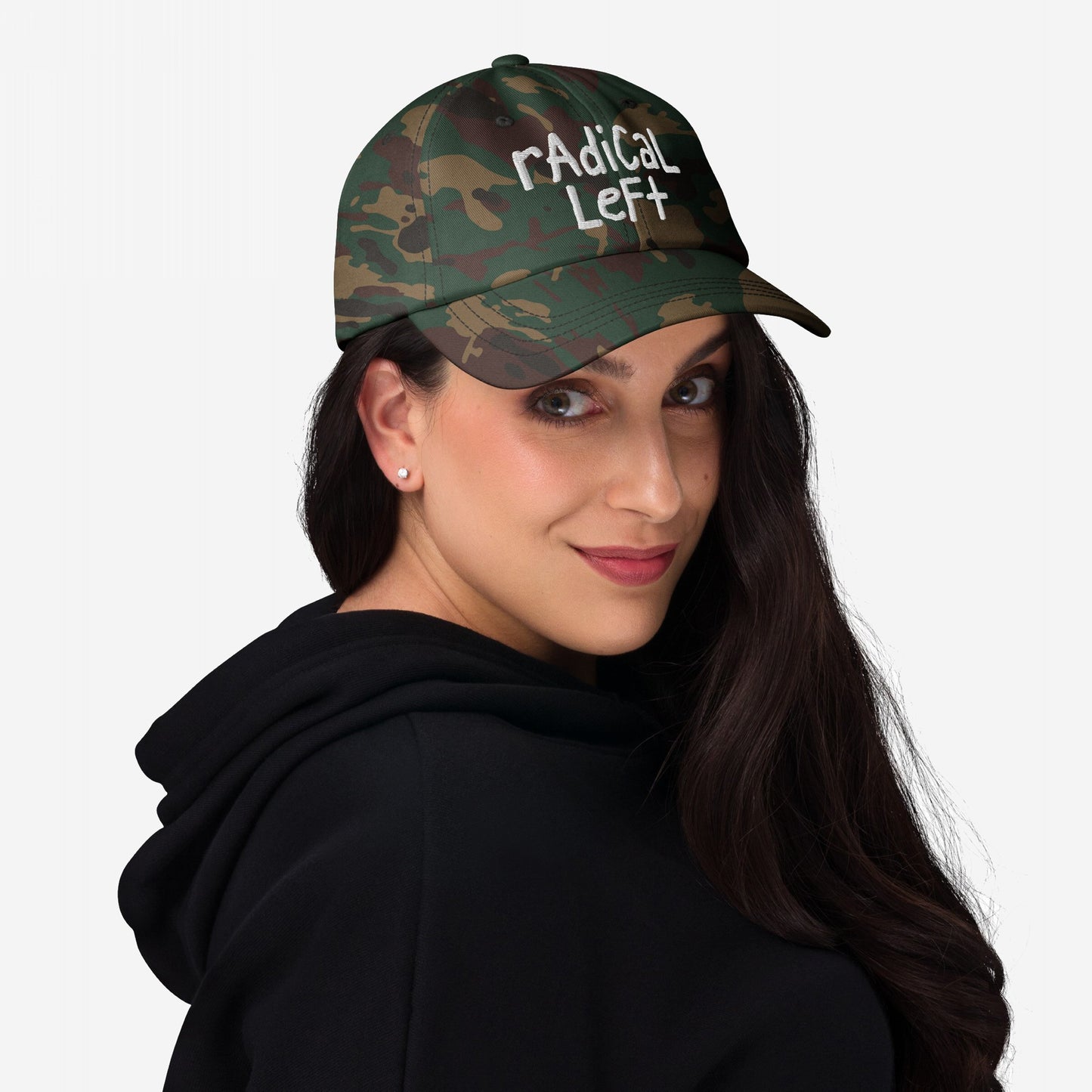 Woman wearing rAdiCal LeFt camouflage baseball cap, black hoodie, and stud earrings, showcasing a rebellious, progressive spirit. Cap features hand-drawn style embroidery, embodying bold, anti-fearmongering energy.