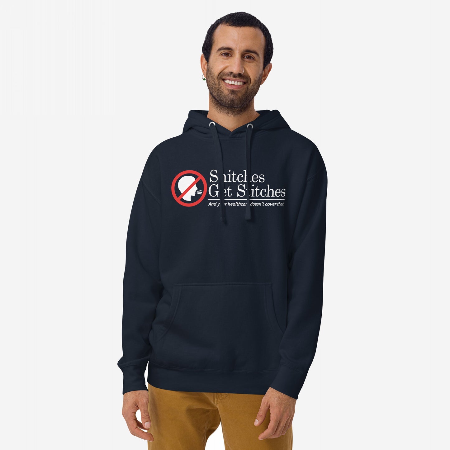 Snitches Get Stitches Hoodie: Model wears navy hoodie featuring a red no symbol over a speaking profile, with bold text Snitches Get Stitches and tagline critiquing healthcare, embodying dark humor and defiance.