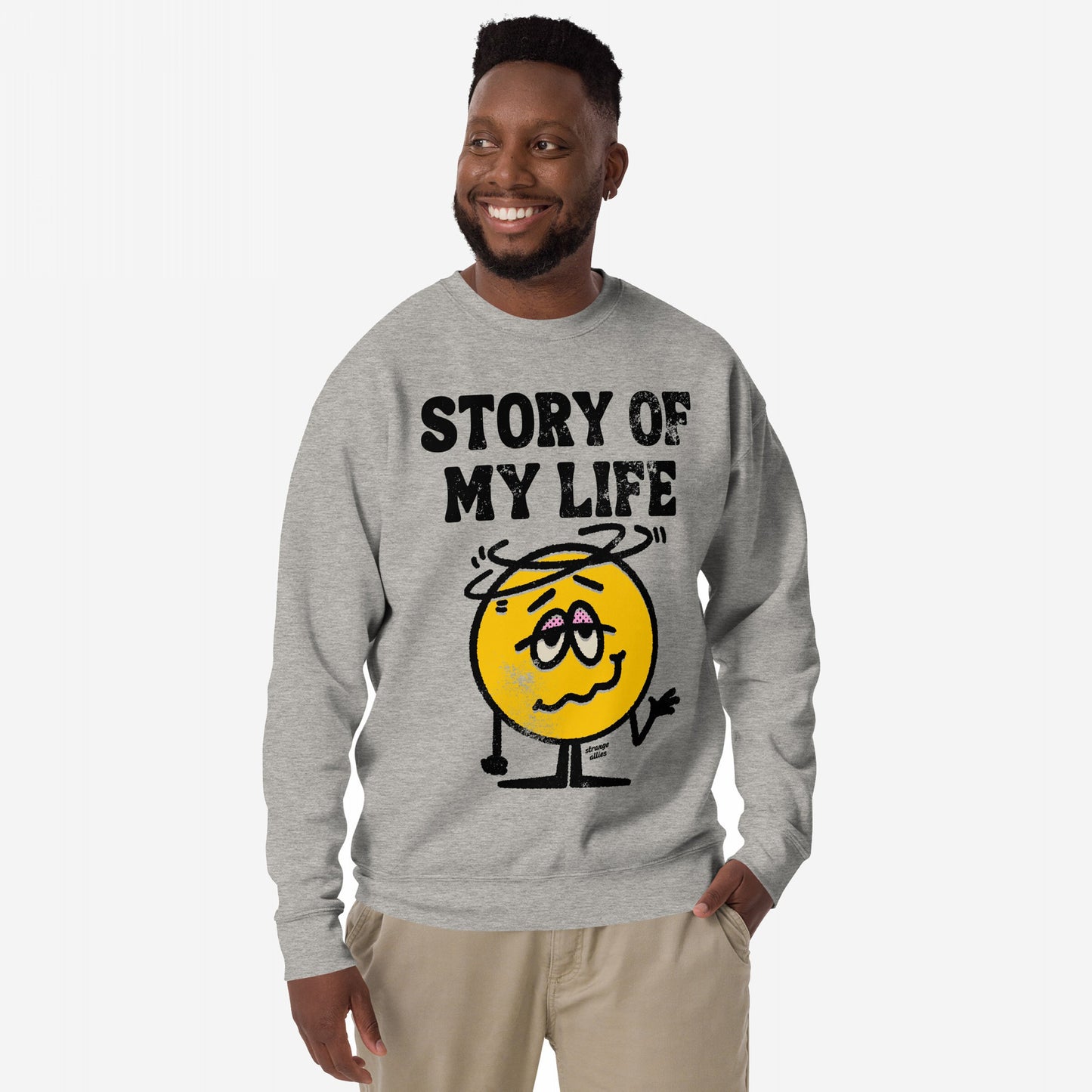 Man wearing the Story Of My Life Sweatshirt featuring a dazed smiley-face and bold text, embodying humor in adversity with style. Hand in pocket, projecting relatable, resilient vibes.