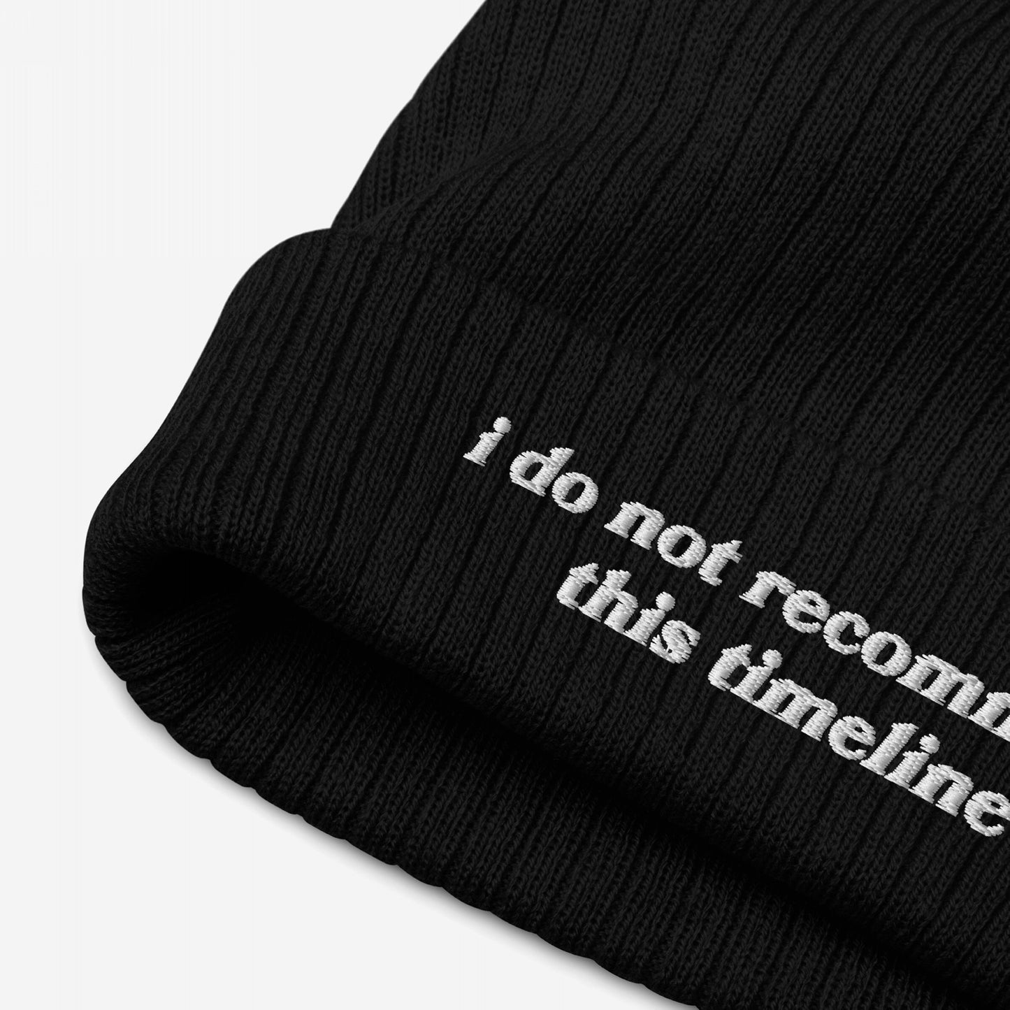 Black rib-knit beanie, Timeline Hat, with white embroidery stating I do not recommend this timeline, reflecting political discontent. Ideal for showing dissent with vintage-inspired lettering.