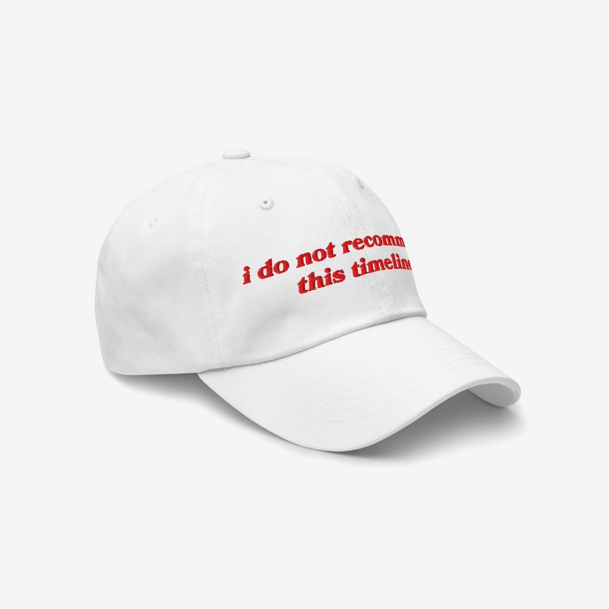 White six-panel baseball cap with the phrase “i do not recommend this timeline.” embroidered in red, reflecting a sarcastic nod to current events, ideal for political humor and protest wear enthusiasts.