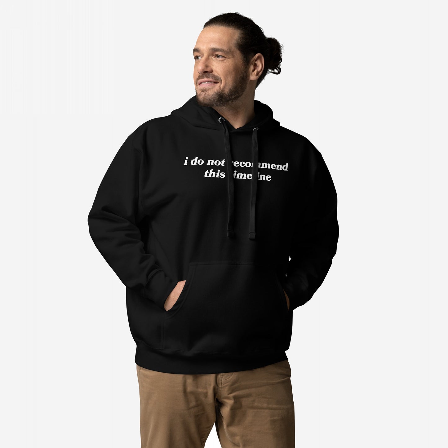 Man models the Timeline Hoodie & Sweatshirt featuring the phrase i do not recommend this timeline in white serif font, blending dystopian style with dry wit, perfect for those embracing skepticism with humor.