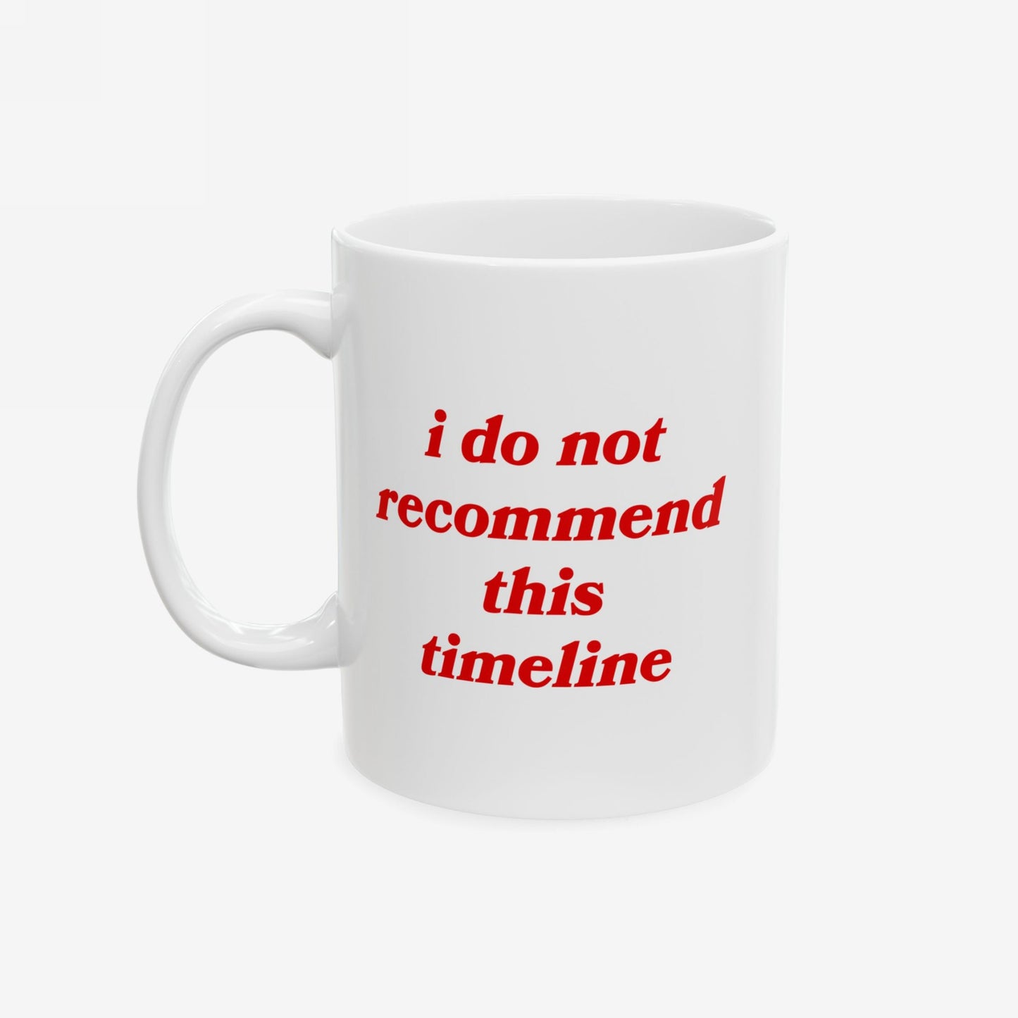 White ceramic Timeline Mug with red text, i do not recommend this timeline, ideal for those facing societal challenges with humor. Features a C-handle, available in two sizes, dishwasher-safe.