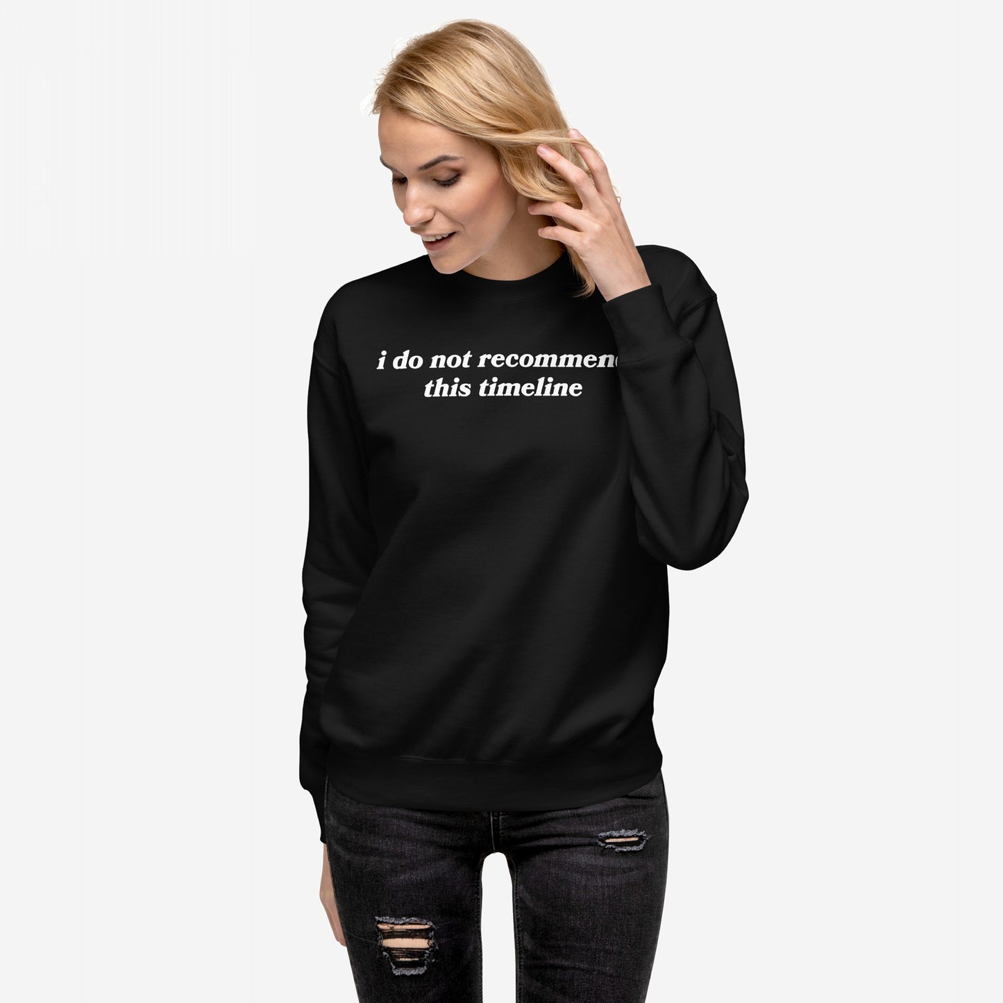 A woman models the Timeline Hoodie & Sweatshirt, featuring i do not recommend this timeline text. The black crewneck exudes sarcasm and style, paired with distressed jeans for a rebellious look.