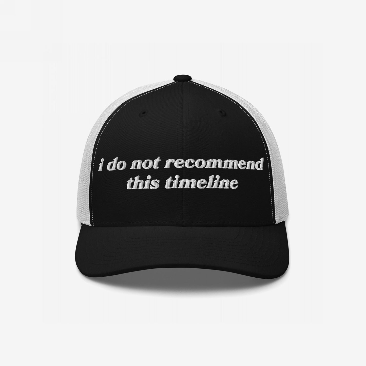 Black-and-white trucker-style baseball cap with the phrase I Do Not Recommend This Timeline embroidered on the front, reflecting a sarcastic, politically-aware message. Ideal for those challenging societal norms.
