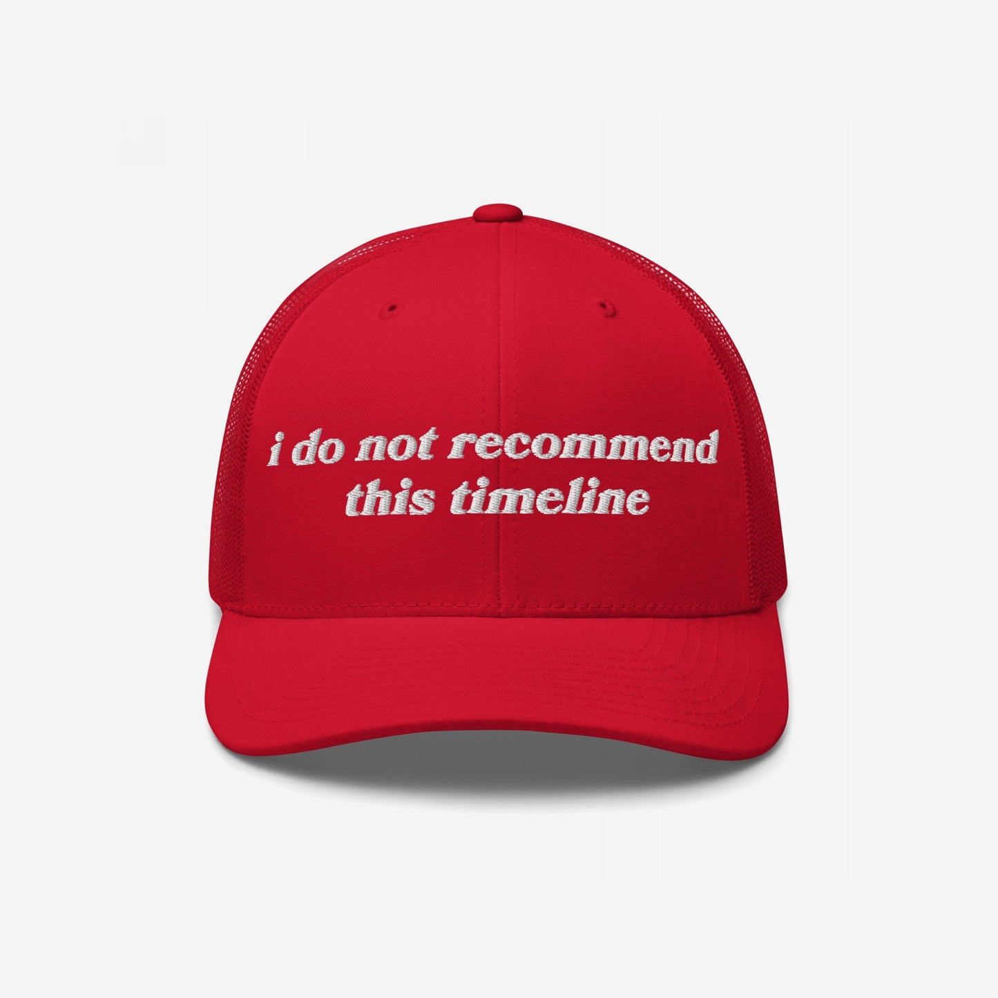Red trucker-style Timeline Hat with white embroidery reading “I do not recommend this timeline,” reflecting a sarcastic stance on current events; ideal for those fueled by political disillusionment.