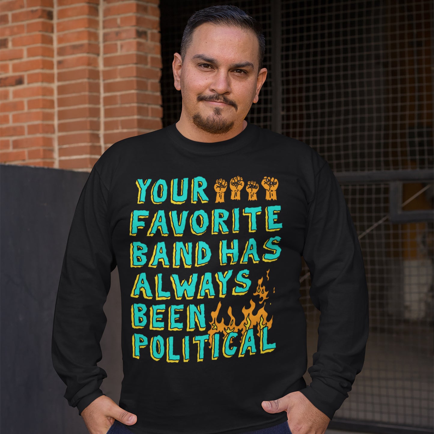 Person wearing Your Favorite Band Has Always Been Political shirt, featuring bold, distressed lettering with raised-fist icons and flames, reflecting a rebellious, punk-inspired style aligned with equality and activism themes.