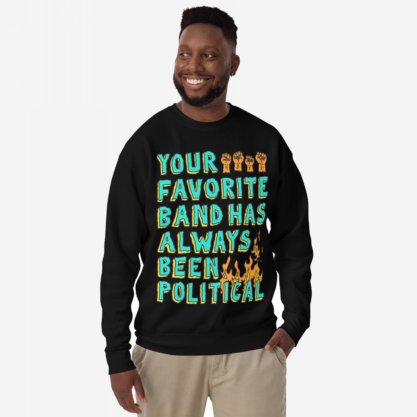 Man models black crewneck sweatshirt with Your Favorite Band Has Always Been Political in aqua-green and yellow letters, featuring orange raised-fist icons and flames, embodying a bold, activist message.