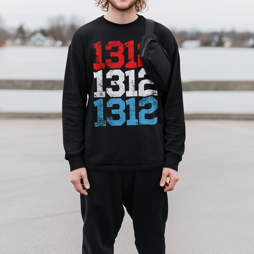 Young man in a black 1312 ACAB T-shirt featuring distressed red, white, and blue numbers, standing by a railing with a sling bag, exemplifying protest style and advocacy for social justice.