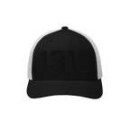Black-and-white trucker cap with 1312 embroidered in black on the front, symbolizing ACAB. The cap features black front panel