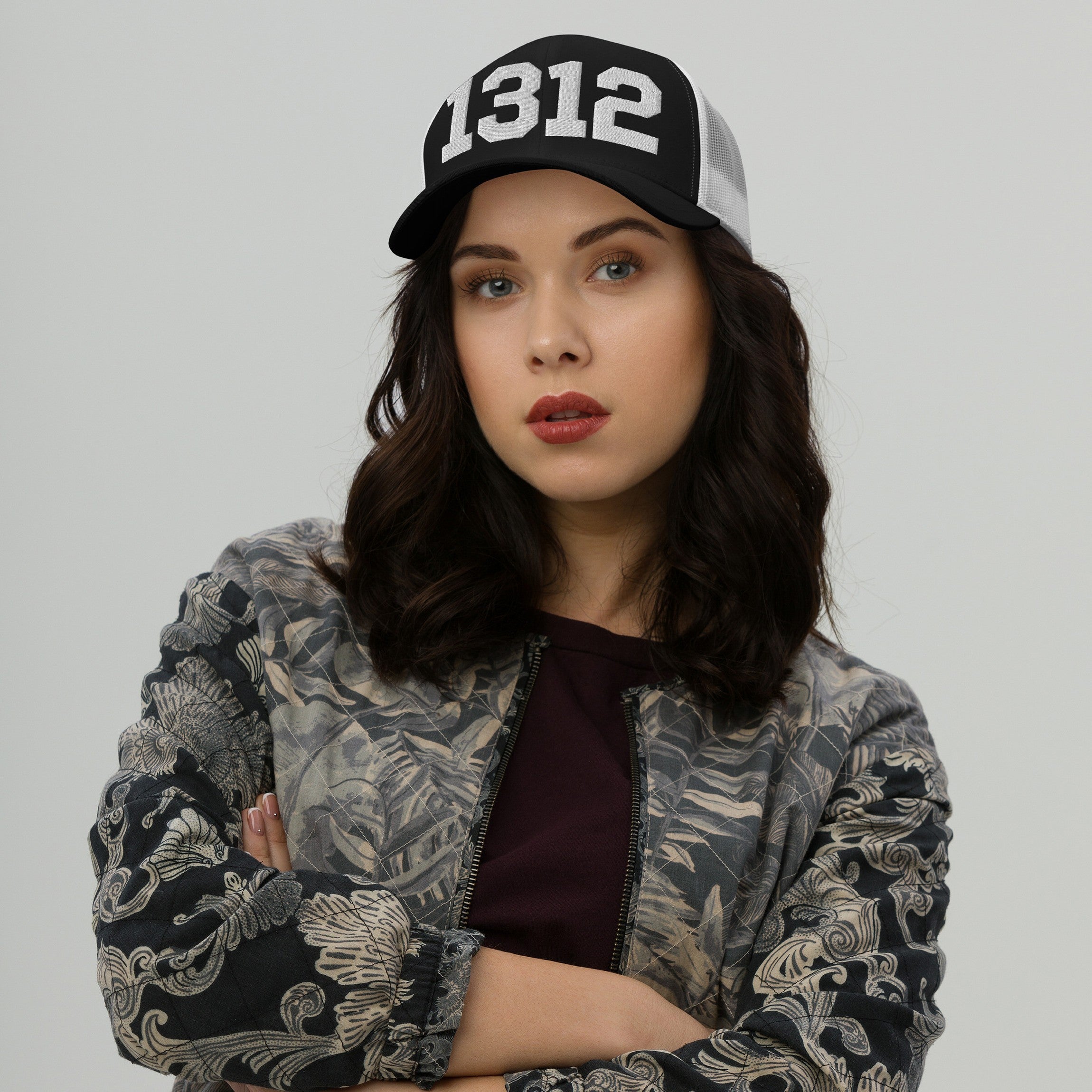Young woman in a black-and-white 1312 ACAB Hat, symbolizing protest, paired with a botanical-patterned bomber jacket, embodying boldness and advocacy against police brutality.