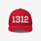 Red trucker-style baseball cap with 1312 embroidered in white on the front, representing the protest code ACAB, symbolizing police accountability and resistance.