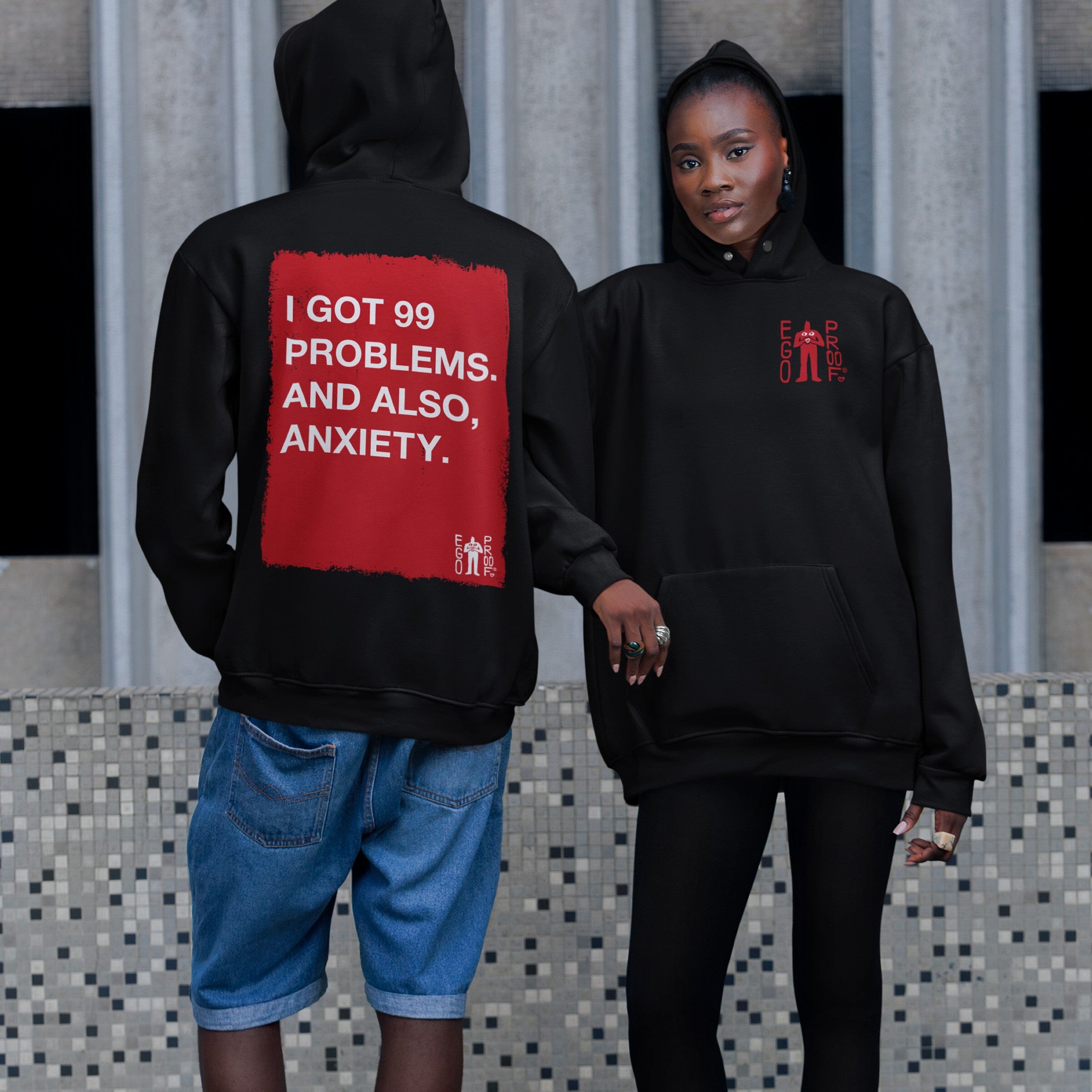 Two models in 99 Problems Hoodie; bold back graphic reads “I GOT 99 PROBLEMS. AND ALSO, ANXIETY.” Front features subtle “EGO PROOF” logo; embodying comfort and unapologetic honesty.