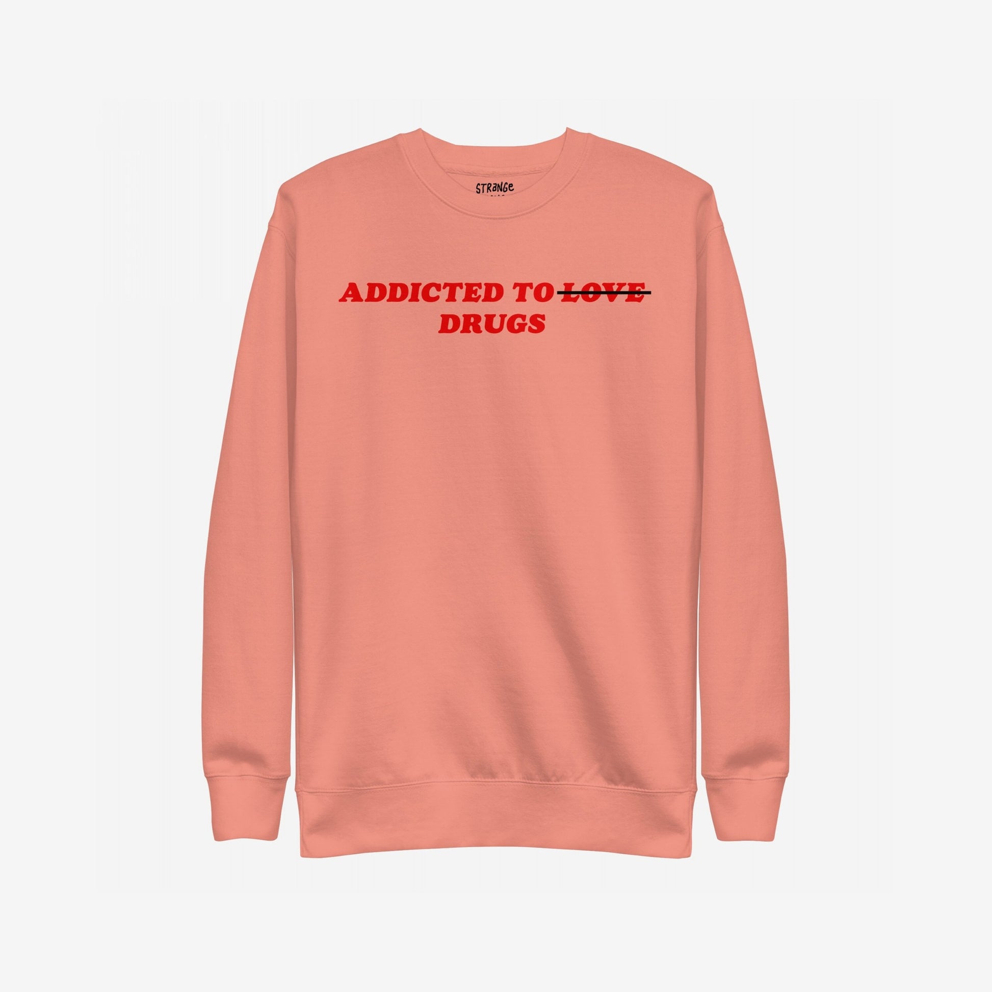 Muted coral crew-neck sweatshirt with bold red text: Addicted to ̶L̶O̶V̶E̶ DRUGS. LOVE is crossed out, symbolizing a raw, honest twist on classic themes.