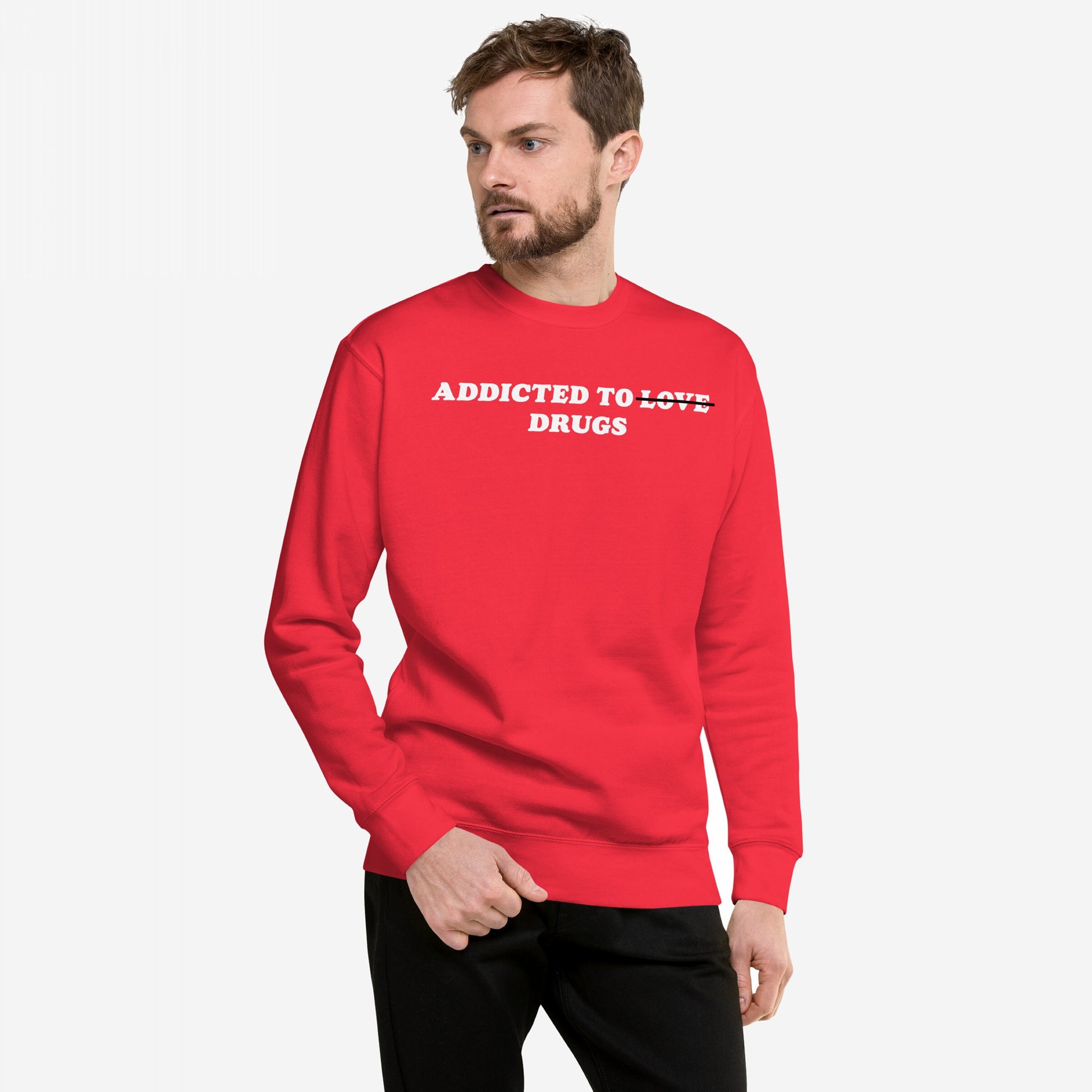 Male model in a bold “Addicted To Love / Drugs” crewneck sweatshirt, where LOVE is crossed out, capturing personal struggle and self-awareness, paired with black pants against a plain backdrop.