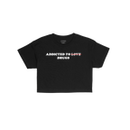 Addicted To Love / Drugs Women's Baby Tee: A cropped black tee with a bold slogan, humorously striking out LOVE for DRUGS in