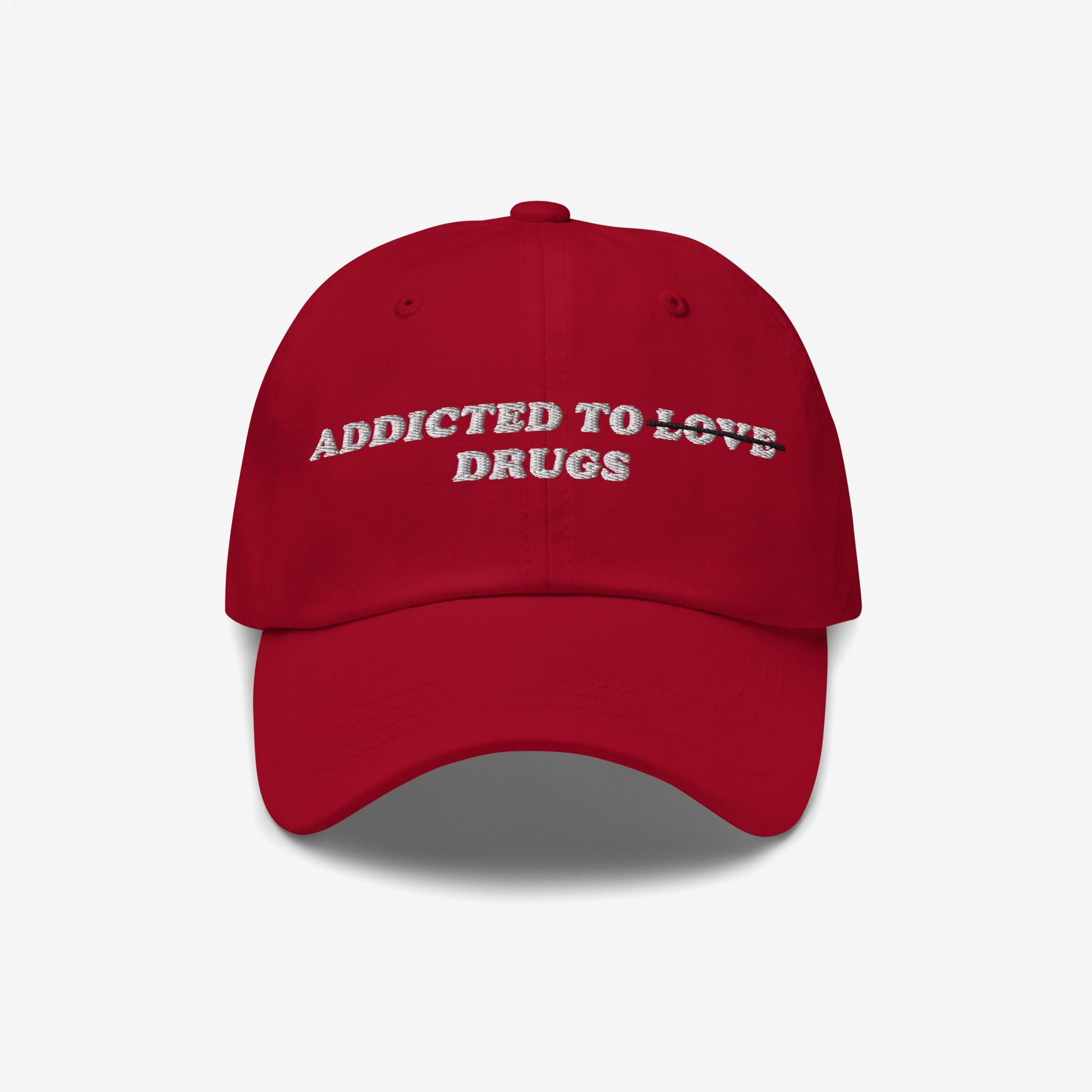 Red embroidered Addicted To Love / Drugs Hat with "Love" crossed out and replaced by "Drugs" in bold retro design.