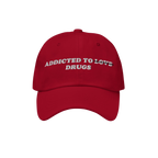 Red embroidered Addicted To Love / Drugs Hat with "Love" crossed out and replaced by "Drugs" in bold retro design.