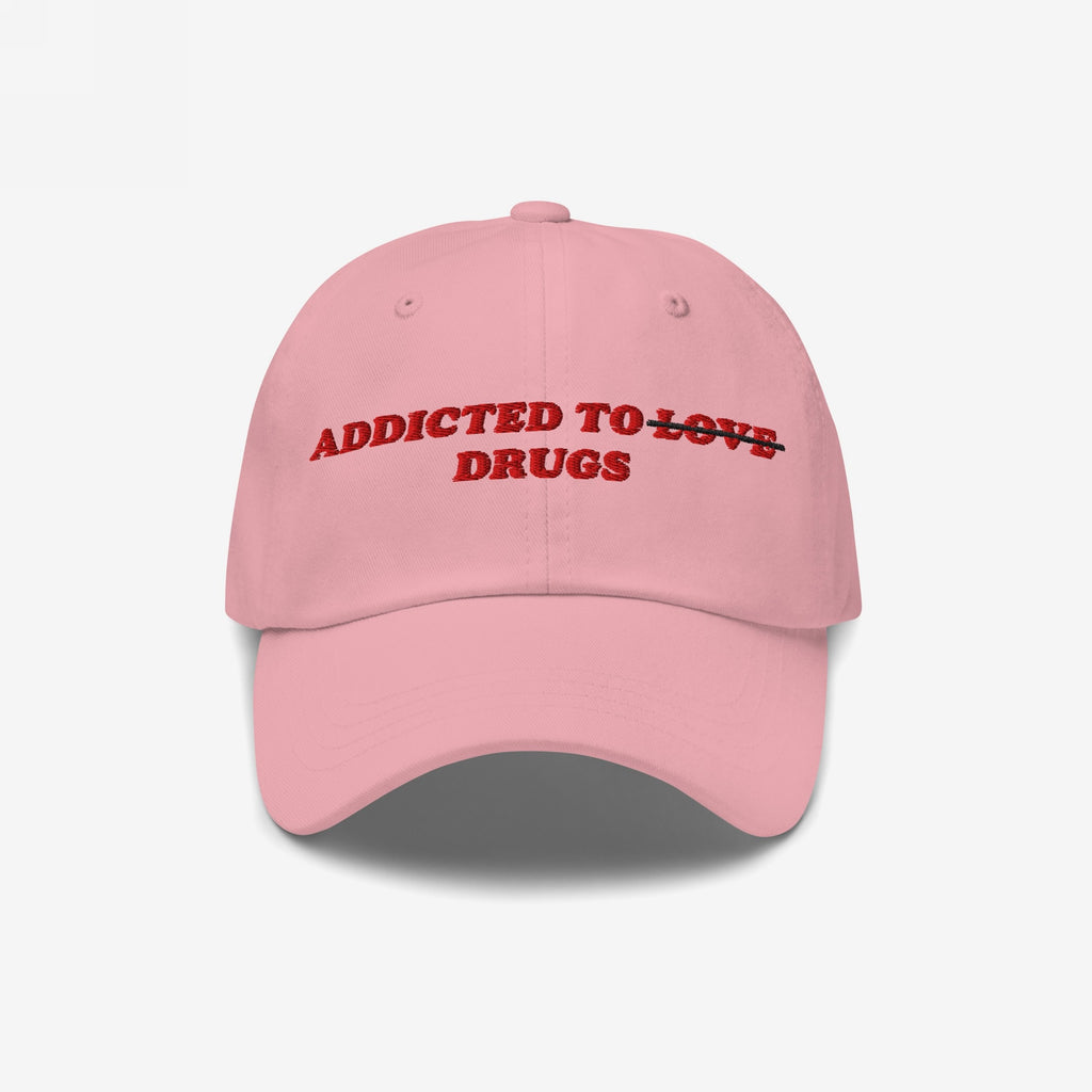 Pink embroidered "Addicted To Love / Drugs Hat" with "Love" crossed out and replaced by "Drugs" in bold red text on front.