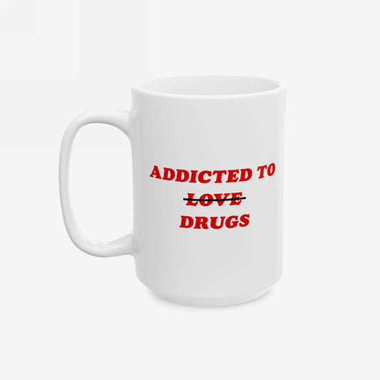 White ceramic mug titled Addicted To Love / Drugs Mug with bold red text, humorously swapping love for drugs through a strikethrough, reflecting mental health awareness and sharp humor.