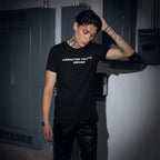 Young man wearing a black Addicted To Love / Drugs Shirt with crossed-out Love text in an industrial setting
