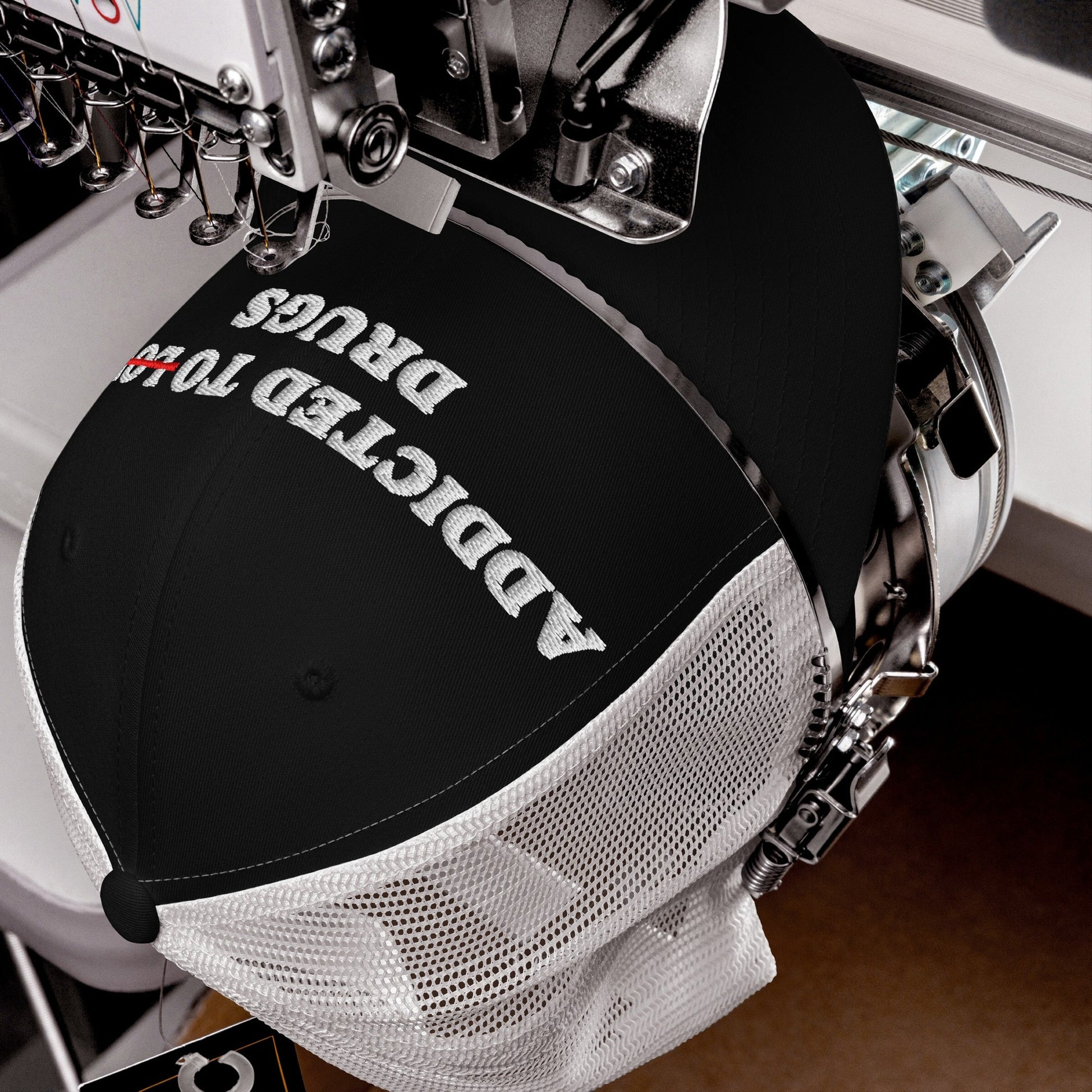 Embroidery machine stitching Adulting Sucks on a black trucker cap with white mesh back, highlighting a bold statement with vintage-style embroidery.