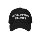 Black cap with “ADULTING SUCKS” embroidered in white, capturing a relatable sentiment for millennials and professionals. 