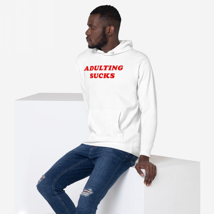 Young man wears the Adulting Sucks Hoodie & Sweatshirt with bold red text, expressing humor and relatability. Paired with ripped jeans, it embodies casual defiance against daily challenges.