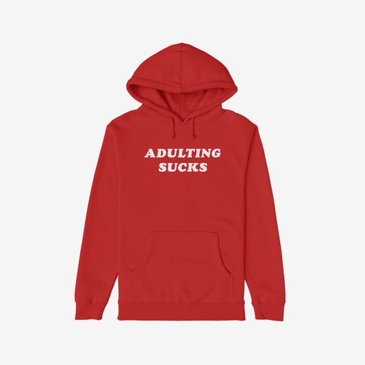 Red pullover hoodie featuring ADULTING SUCKS in bold white letters, exemplifying humor and relatable design. Ideal for self-expression, supporting NAMI's mental health initiatives. Part of a socially-conscious apparel line.