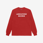 Red long-sleeve Adulting Sucks Shirt with bold white letters on chest, humorously highlighting the struggles of adult life, perfect for casual wear and self-expression. Supports NAMI through proceeds.