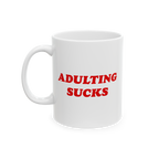 White ceramic mug with bold red “Adulting Sucks” text, shown with the handle on the left side against a plain backdrop