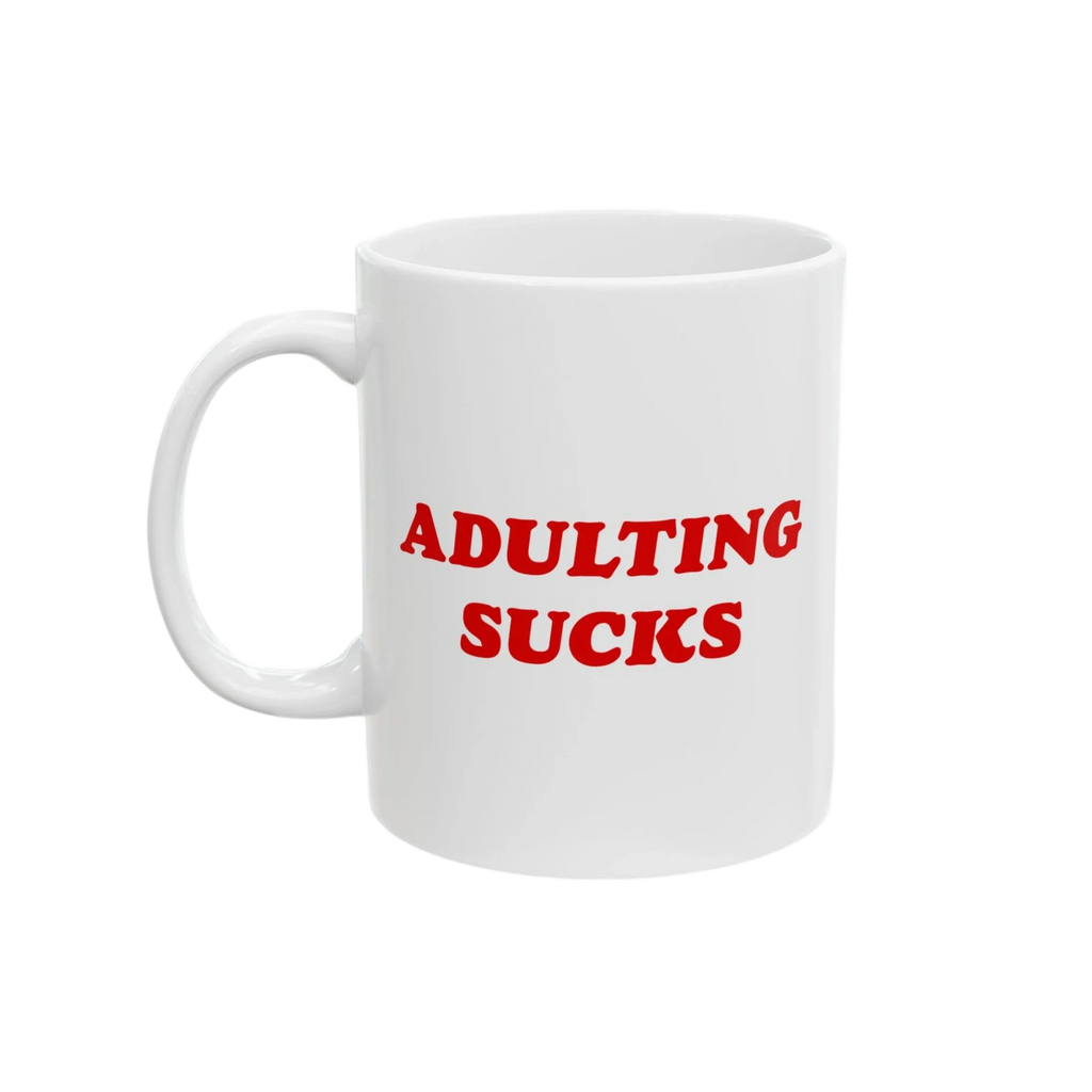 White ceramic mug with bold red “Adulting Sucks” text, shown with the handle on the left side against a plain backdrop