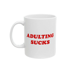 White ceramic mug with bold red “Adulting Sucks” text, shown with the handle on the left side against a plain backdrop