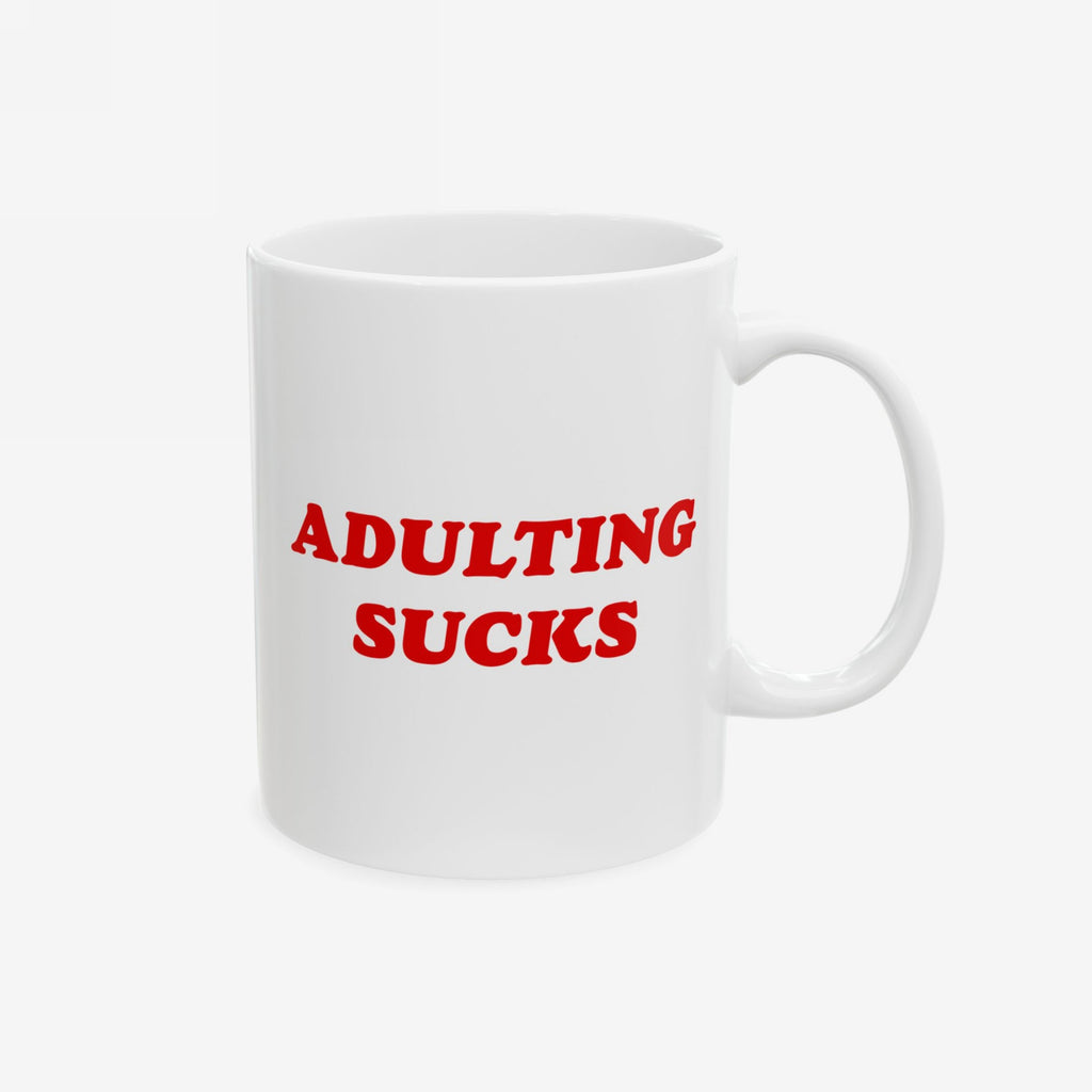 Classic office mug featuring the phrase “Adulting Sucks” in red text, photographed with a handle on the right