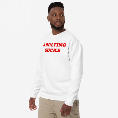 Man in Adulting Sucks crewneck sweatshirt, featuring bold red text, expressing humor in everyday challenges. He's paired it with light pants, embodying the relatable theme of grown-up burnout.