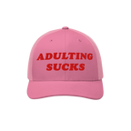 The Adulting Sucks Hat features bold red embroidery on a pink trucker-style cap, encapsulating the struggle against adult res