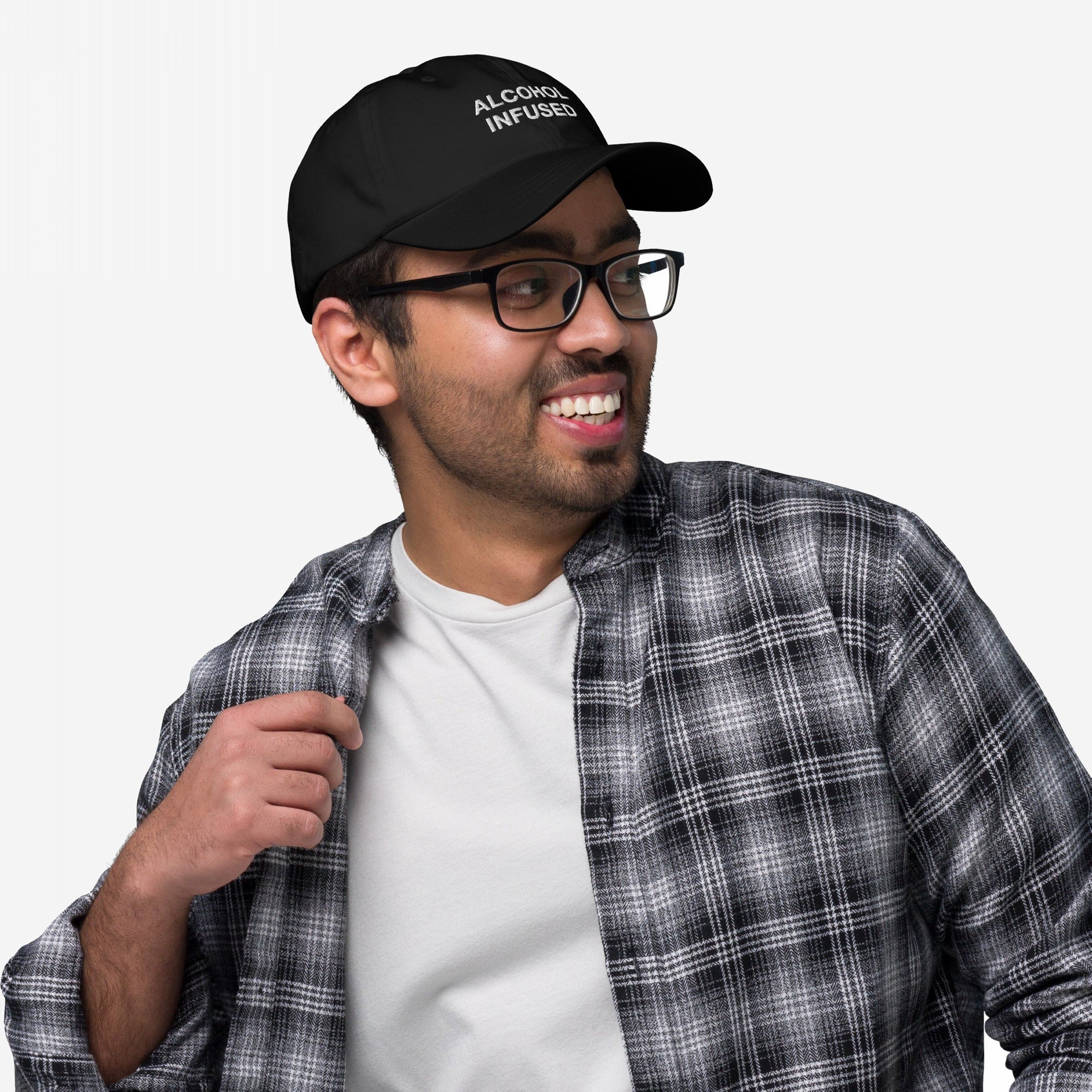 Young man models the Alcohol Infused hat, featuring bold embroidery on a black baseball cap. Paired with a casual plaid shirt, the hat embodies a playful, edgy statement.