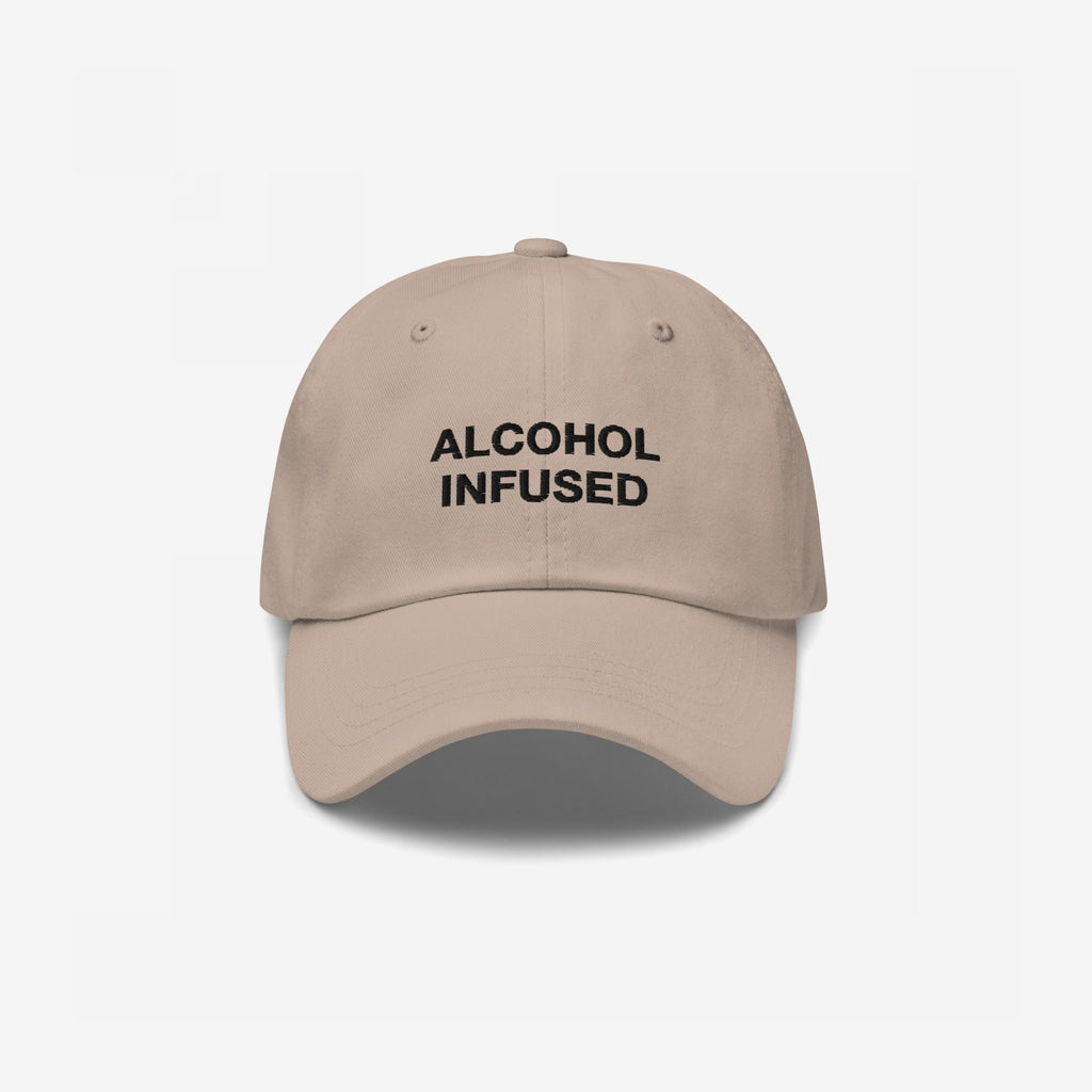 Alcohol Infused Hat: A tan baseball-style cap with bold black embroidery reading “ALCOHOL INFUSED,” embodying edgy humor and irreverence, perfect for making a statement at casual gatherings.