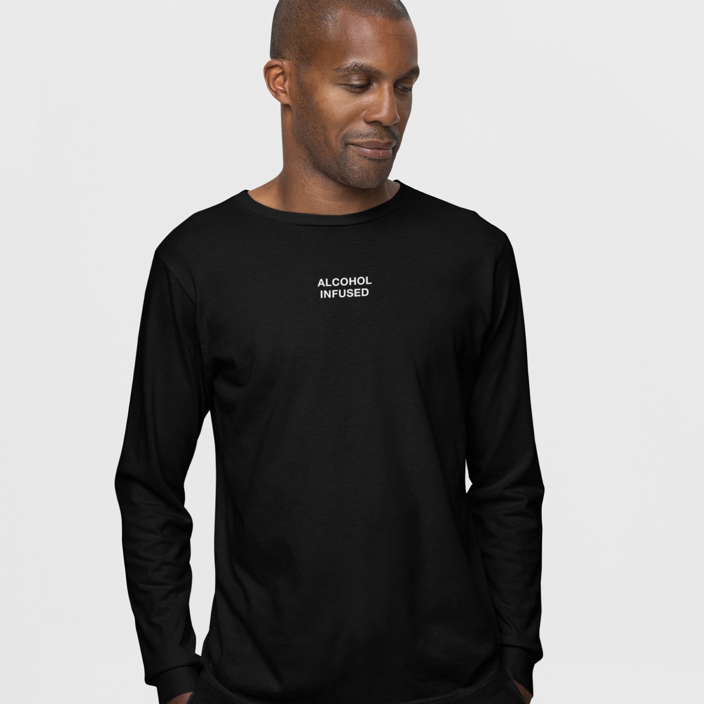 Man wearing the Alcohol Infused T-shirt featuring subtle white lettering on a black long-sleeve, embodying a carefree, unapologetic vibe, ideal for those embracing chaos with humor and style.